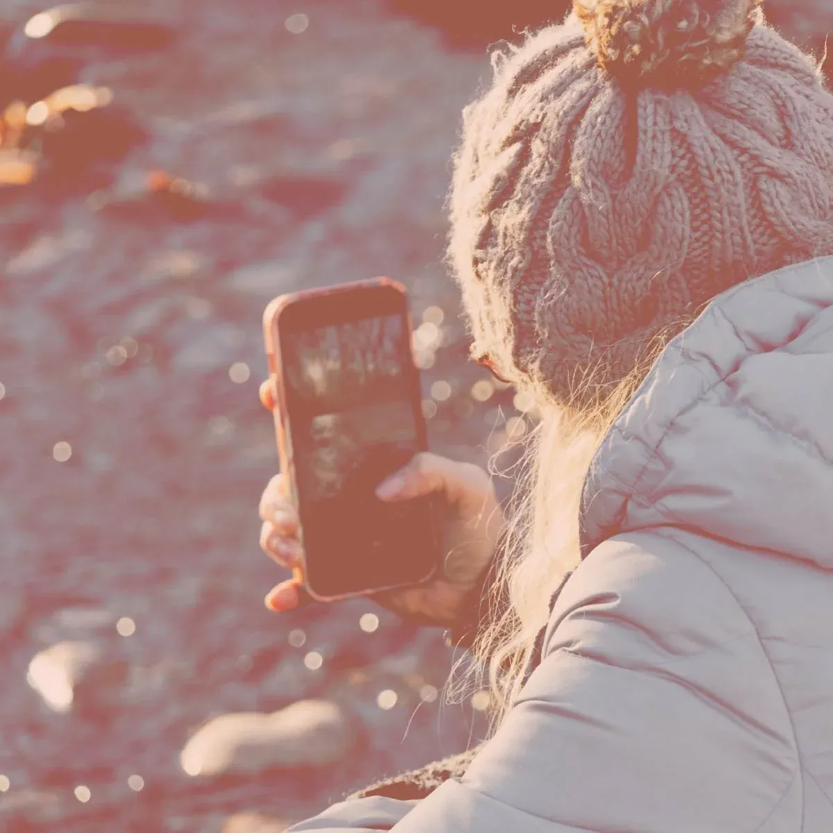 Mujer con gorro y abrigo usando un smartphone en un entorno natural para bienestar digital